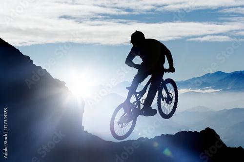 springender Mountainbiker im Gebirge im Gegenlicht